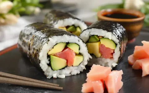 Trzy rolki maki sushi z łososiem i awokado, podane z imbirem i sosem sojowym. Pyszne maki sushi co to? To idealna przekąska!
