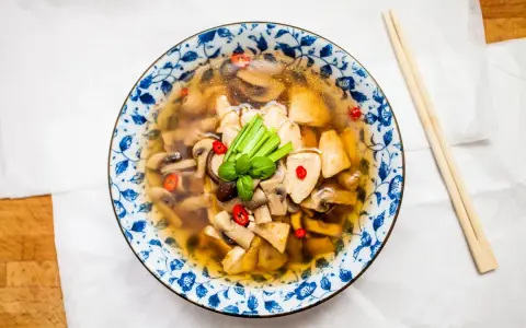 Aromatyczna zupa tom yum z kurczakiem i grzybami, ozdobiona chili i zieloną cebulką. Idealna na chłodne dni.