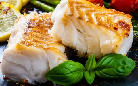 Dwa kawałki pieczonego dorsza atlantyckiego, podane z cytryną, szparagami i pomidorkami. Który lepszy?