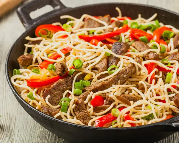 Makaron chow mein z wołowiną, papryką i szczypiorkiem w woku.