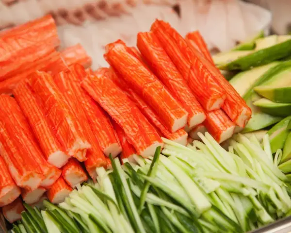 Paluszki surimi, pokrojony ogórek i awokado. Idealne składniki do sushi, które wyjaśniają, surimi co to jest.