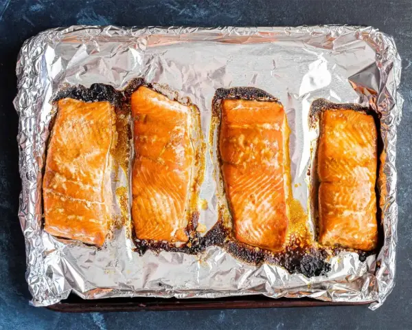 Cztery kawałki łososia pieczone na folii aluminiowej, gotowe do dalszego przygotowania, np. jak przygotować łososia do sushi.