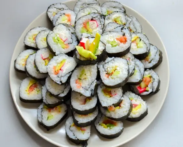 Talerz sushi z paluszkami krabowymi, awokado i łososiem. Idealne do nauki, jak przygotować paluszki krabowe do sushi.