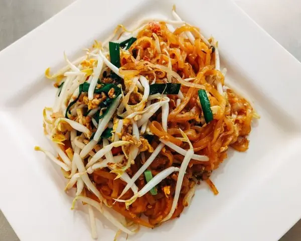 Pyszne danie Pad Thai z makaronem ryżowym, kiełkami fasoli mung, jajkiem i zieloną cebulką, polane charakterystycznym pad thai sosem.