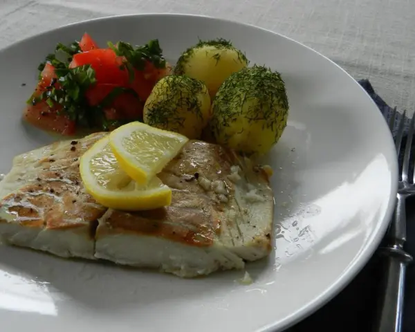 Filet z dorsza z piekarnika w folii, podany z ziemniakami i pomidorami.