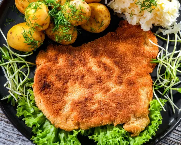 Chrupiący schabowy w panko, podany z młodymi ziemniaczkami, surówką i świeżą sałatą. Prawdziwa uczta dla podniebienia!