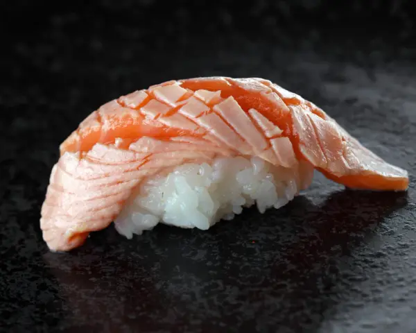 Jak wygląda sushi: delikatny ryż i soczysty, lekko opalony łosoś ułożony w wachlarz.