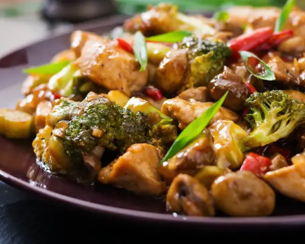 Pyszny stir fry z kurczakiem, brokułami i grzybami w sosie. Danie wygląda apetycznie i jest bogate w kolory.