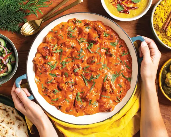 Pyszny **butter chicken przepis oryginalny** w kremowym sosie, podany z ryżem, sałatką i chlebkiem naan.