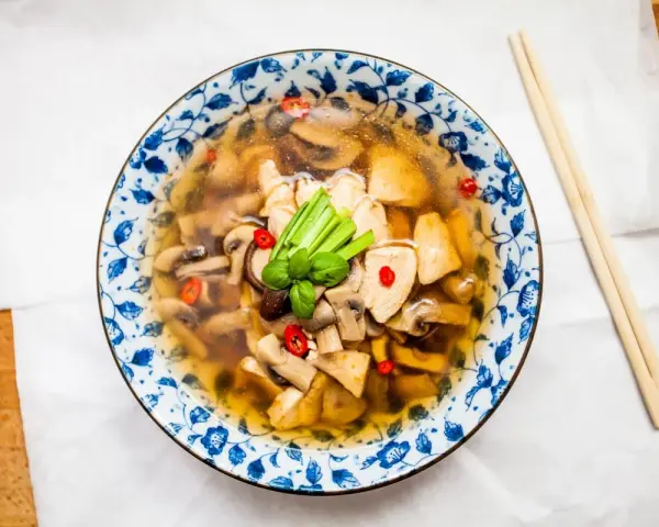Aromatyczna zupa tom yum z kurczakiem i grzybami, ozdobiona chili i zieloną cebulką. Idealna na chłodne dni.