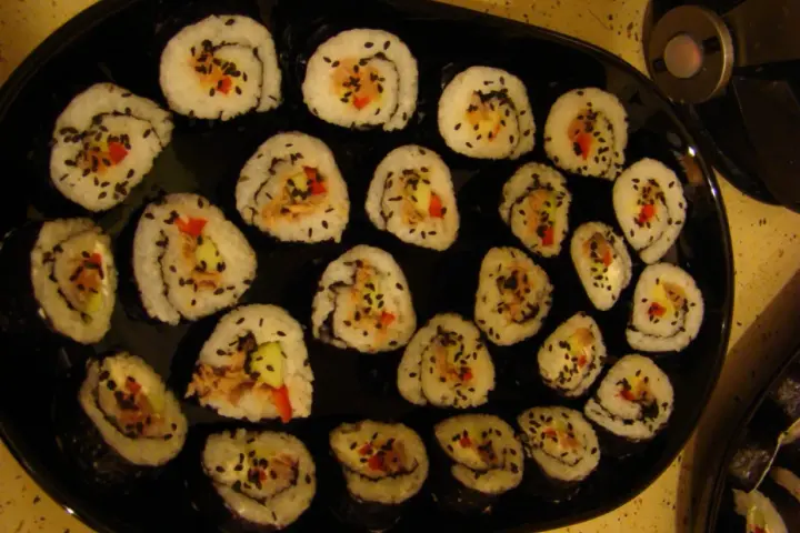 Roladki sushi z tuńczykiem, ogórkiem i papryką, posypane czarnym sezamem. Idealne, gdy zastanawiasz się, jak przygotować tuńczyka do sushi.