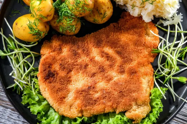 Chrupiący schabowy w panko, podany z młodymi ziemniaczkami, surówką i świeżą sałatą. Prawdziwa uczta dla podniebienia!