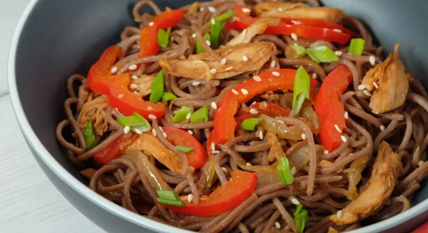Makaron soba przepis: danie z makaronem gryczanym, kurczakiem, papryką i szczypiorkiem, posypane sezamem.
