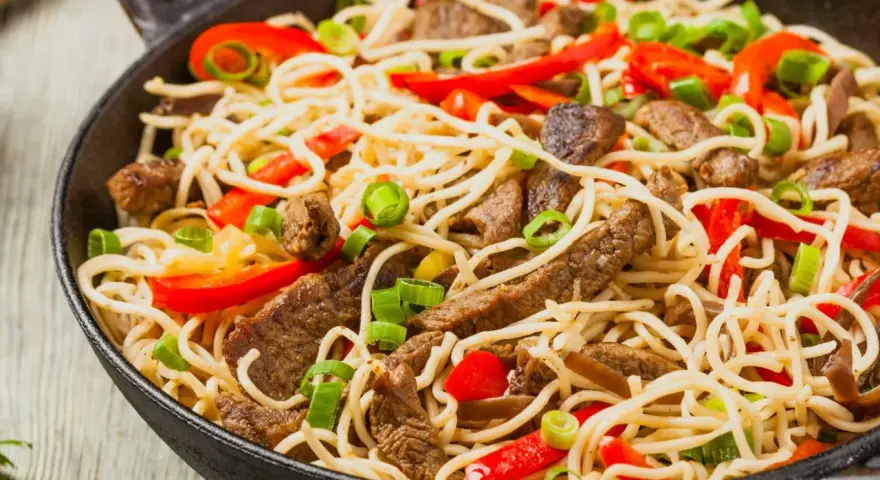 Makaron chow mein z wołowiną, papryką i szczypiorkiem w woku.