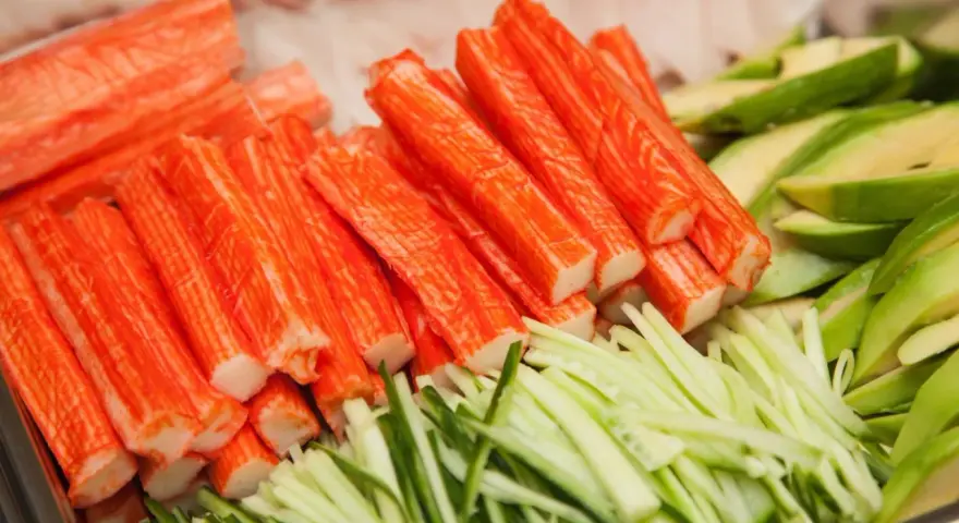 Paluszki surimi, pokrojony ogórek i awokado. Idealne składniki do sushi, które wyjaśniają, surimi co to jest.
