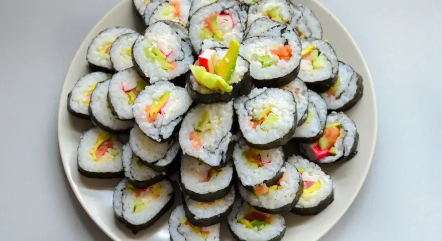 Talerz sushi z paluszkami krabowymi, awokado i łososiem. Idealne do nauki, jak przygotować paluszki krabowe do sushi.