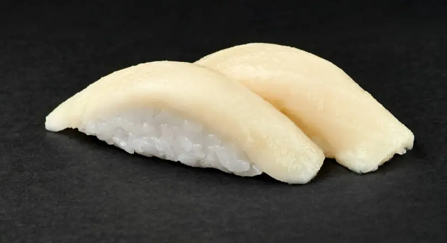 Dwa kawałki sushi z rybą maślaną na czarnym tle. Delikatna ryba idealnie komponuje się z ryżem.