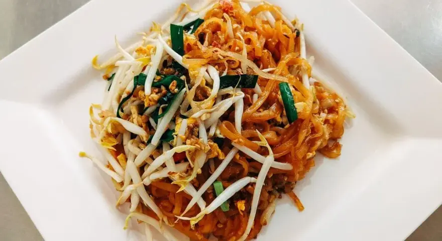 Pyszne danie Pad Thai z makaronem ryżowym, kiełkami fasoli mung, jajkiem i zieloną cebulką, polane charakterystycznym pad thai sosem.