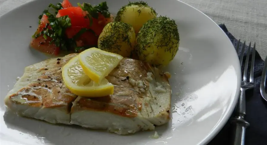 Filet z dorsza z piekarnika w folii, podany z ziemniakami i pomidorami.
