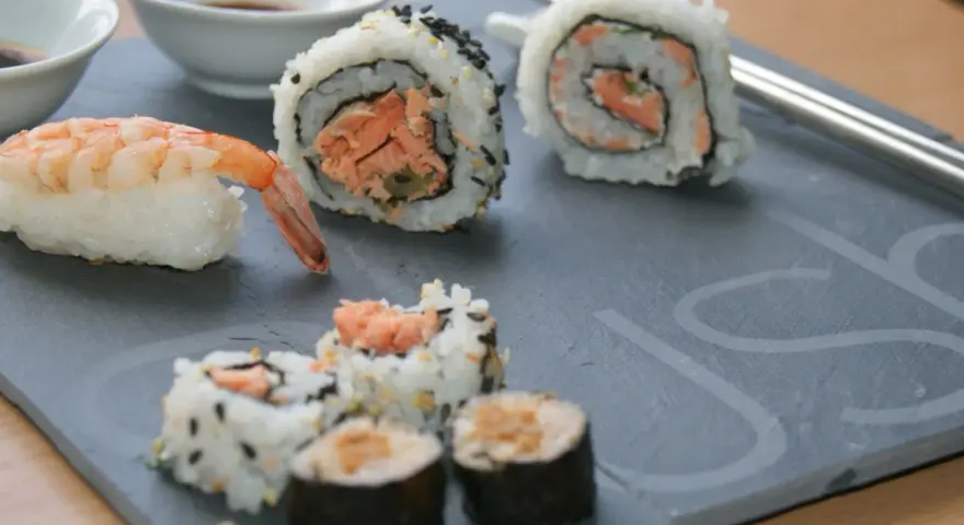 Jak przygotować krewetki do sushi? Na talerzu sushi z krewetką i rolkami z łososiem.