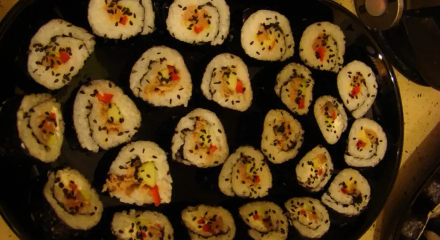 Roladki sushi z tuńczykiem, ogórkiem i papryką, posypane czarnym sezamem. Idealne, gdy zastanawiasz się, jak przygotować tuńczyka do sushi.