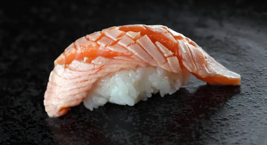 Jak wygląda sushi: delikatny ryż i soczysty, lekko opalony łosoś ułożony w wachlarz.