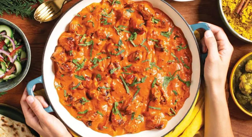 Pyszny **butter chicken przepis oryginalny** w kremowym sosie, podany z ryżem, sałatką i chlebkiem naan.