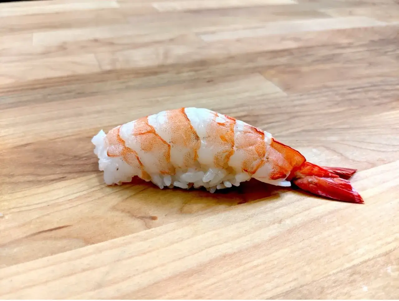 Jak przygotować krewetki do sushi: gotowy nigiri z krewetką na desce.