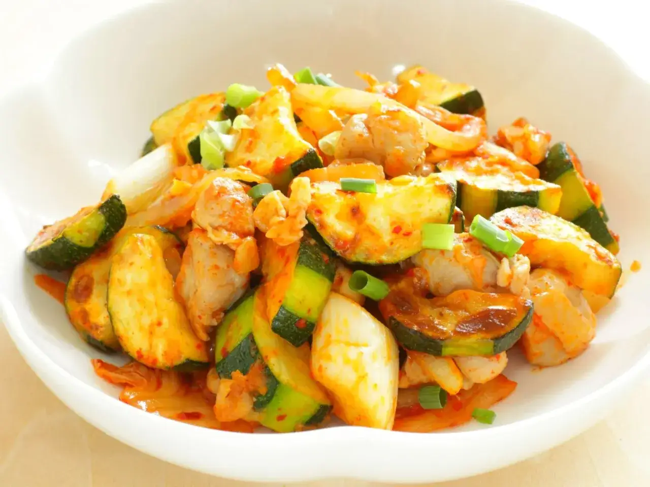 Pyszny stir fry z kurczakiem i cukinią, doprawiony na ostro, posypany szczypiorkiem.