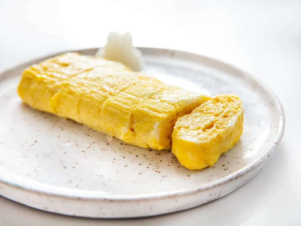 Tamago to japoński omlet, zwinięty w rolkę i pokrojony. Pyszne danie, które warto spróbować!