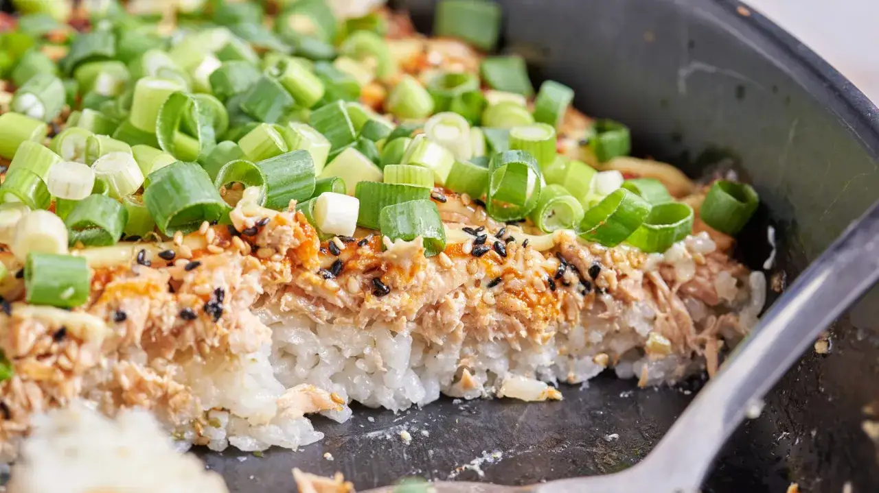 Pyszne sushi z pieczonym łososiem, ryżem i szczypiorkiem, posypane sezamem.