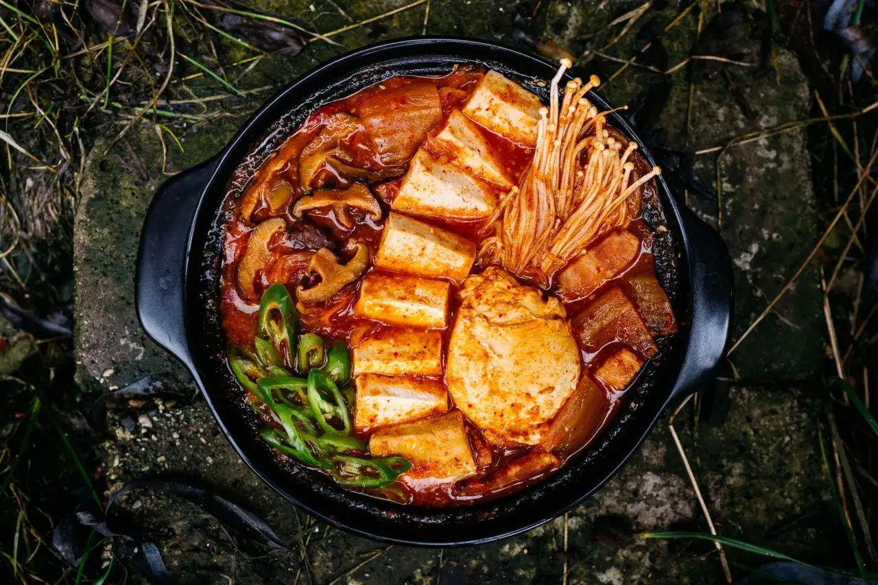 Gorąca zupa z kimchi z tofu, grzybami i cienkimi nitkami grzybów enoki. Idealna na chłodne dni.