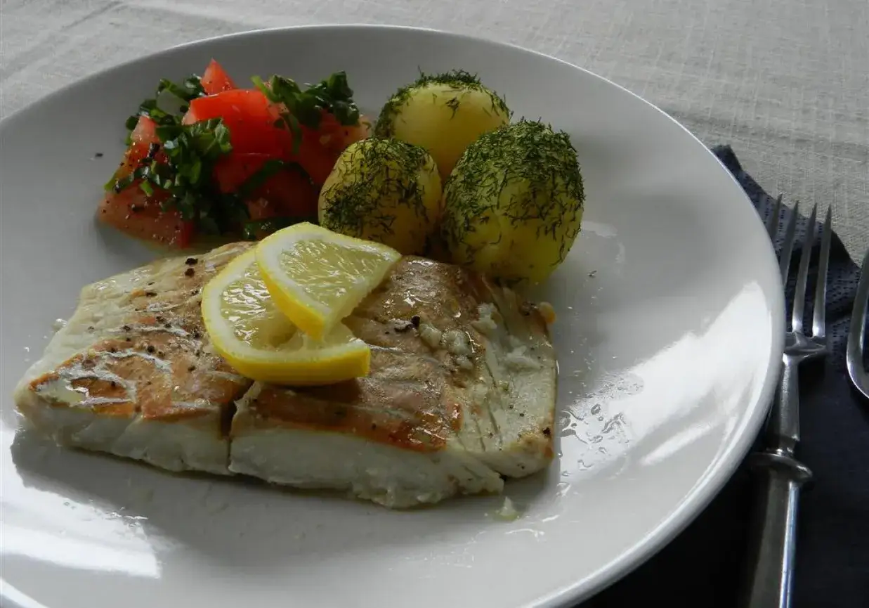 Pyszny filet z dorsza z piekarnika w folii, podany z ziemniakami i pomidorami.