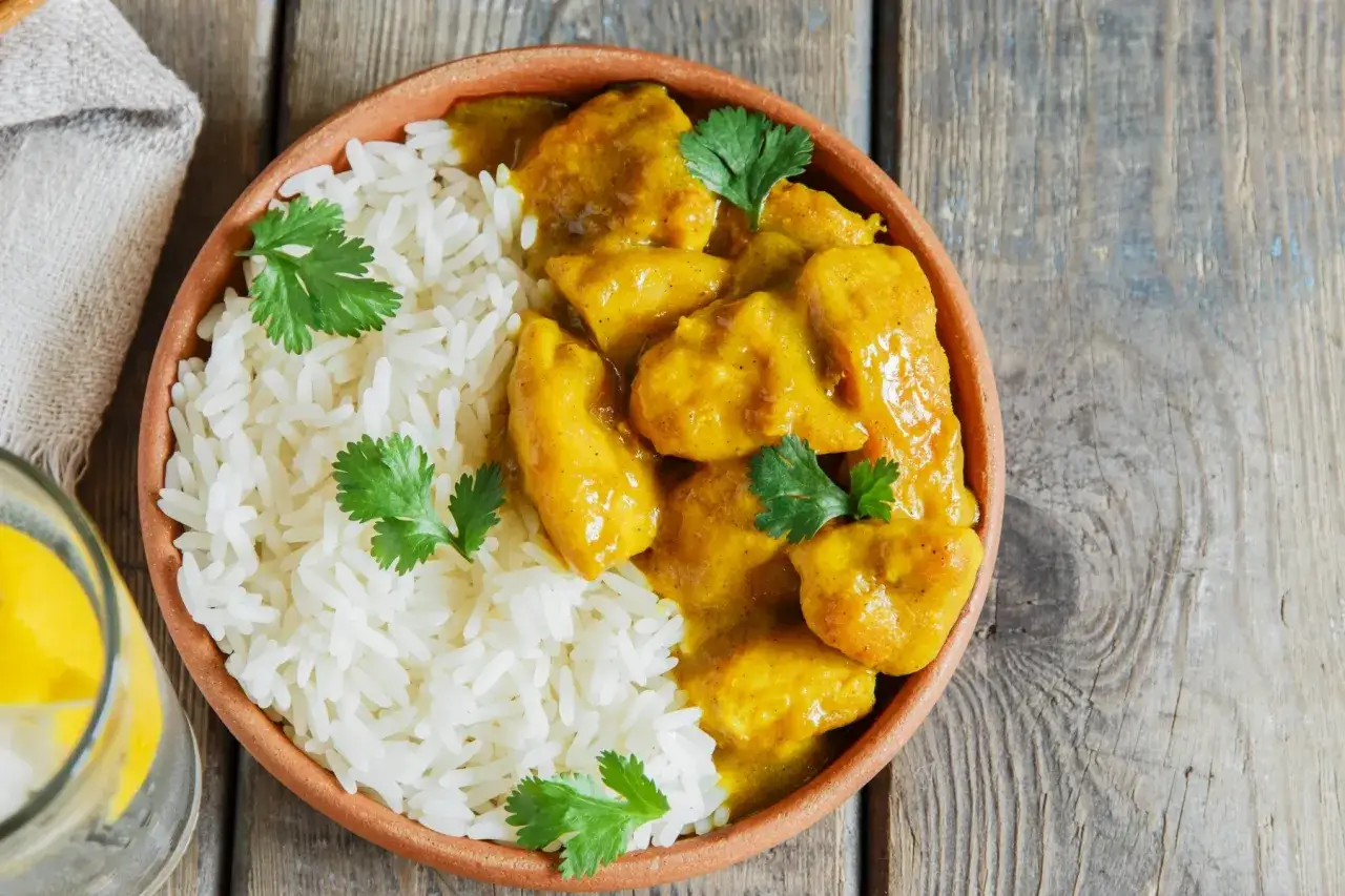 Prosty sos do ryżu z kurczakiem w żółtym sosie curry, udekorowany świeżą kolendrą.