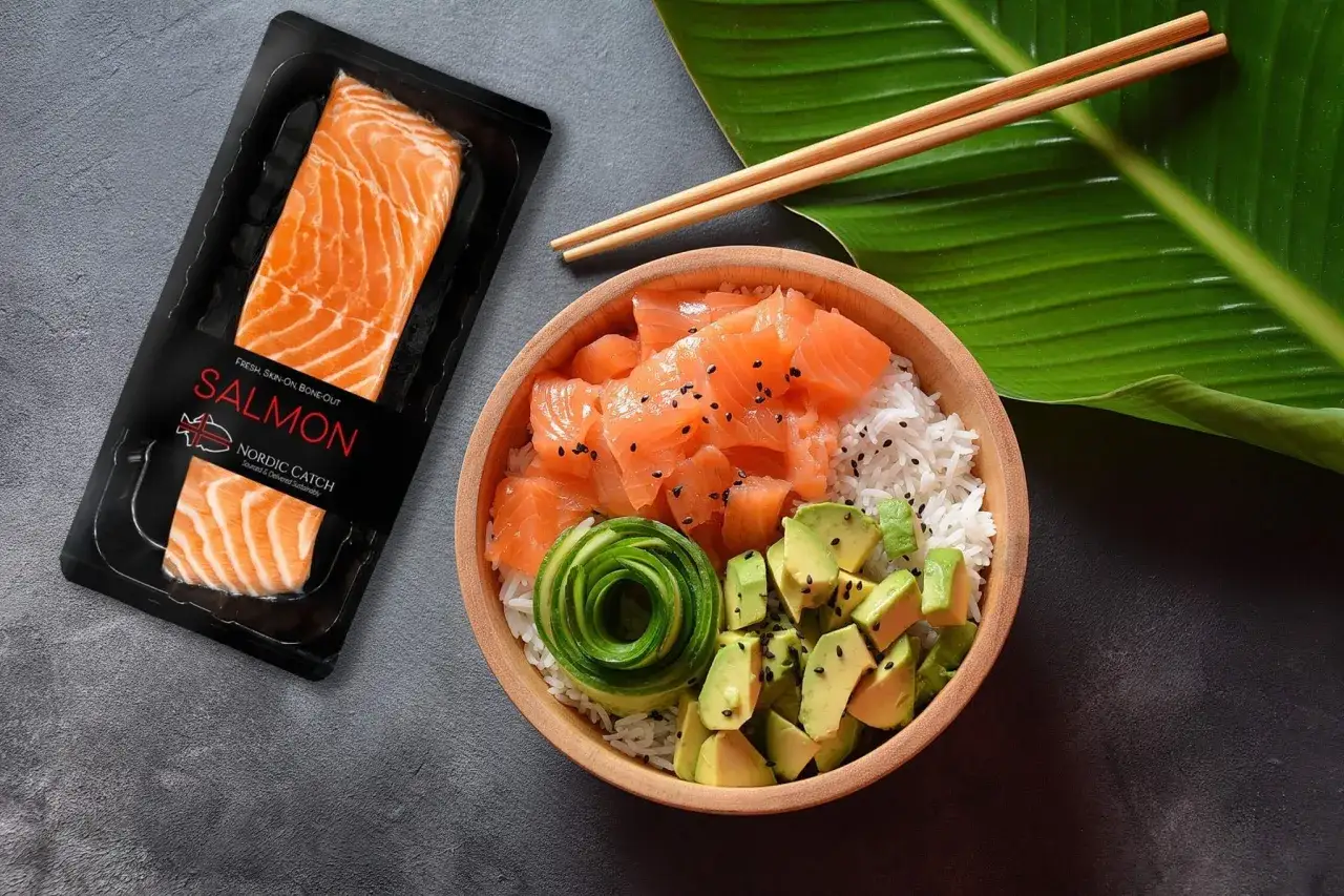 Gdzie kupić surowego łososia do sushi? Opakowanie świeżego łososia Nordic Catch obok miski z ryżem, awokado i łososiem.