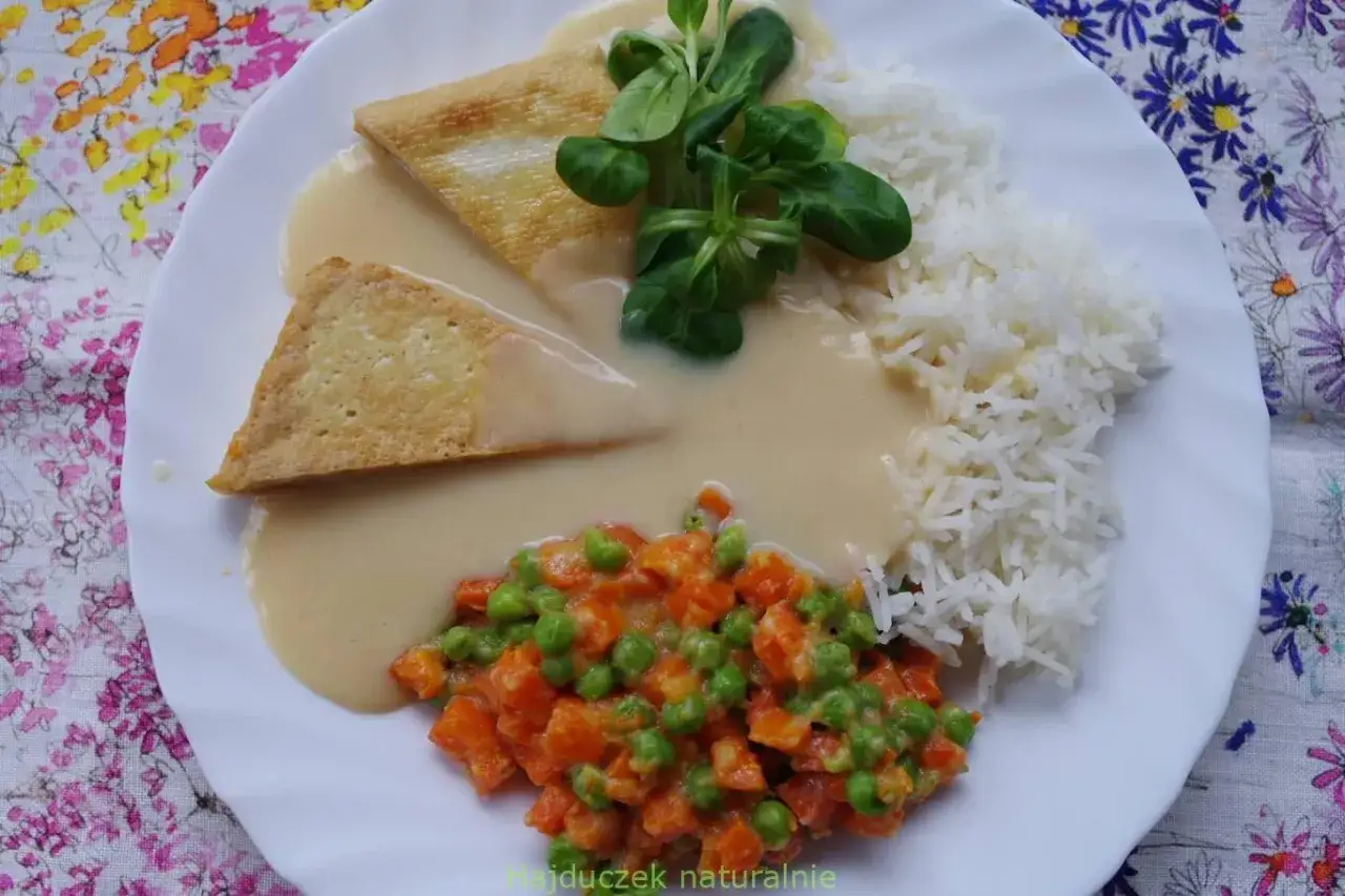 Talerz z ryżem, warzywami i dwoma kawałkami smażonego tofu w sosie śmietanowym do ryżu.