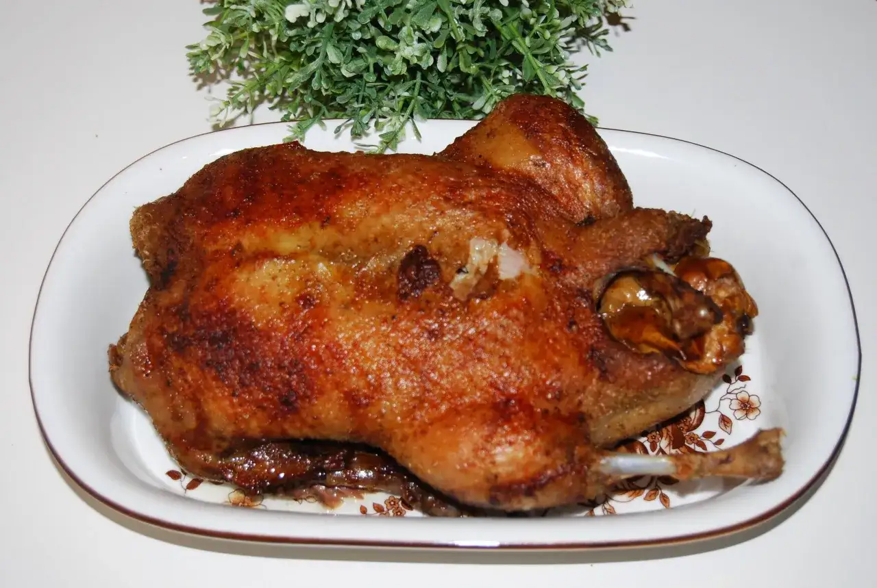 Apetyczna kaczka po tonkińsku, pieczona do perfekcji, z chrupiącą skórką, podana na talerzu z ozdobnym wzorem.