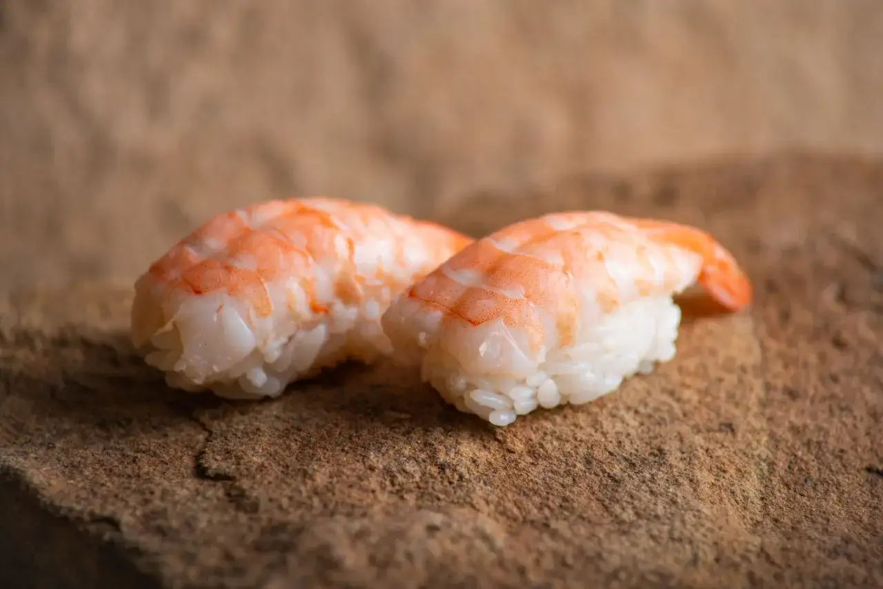 Dwa kawałki sushi z krewetkami na kamiennym tle. Idealne do nauki, jak przygotować krewetki do sushi.
