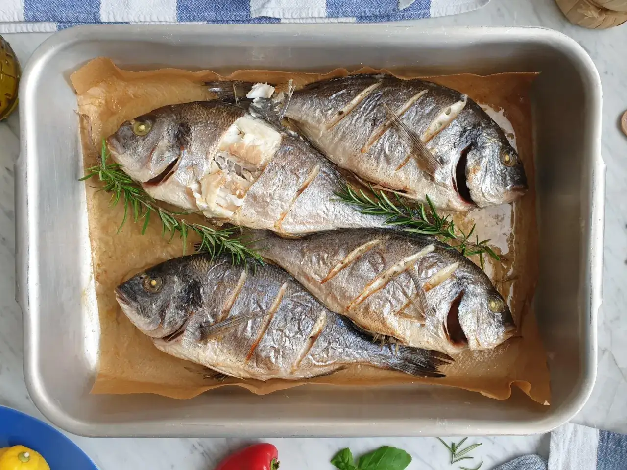 Pieczone ryby w blasze z gałązkami rozmarynu. Czy rozmaryn pasuje do ryby? Tak, dodaje wspaniałego aromatu!