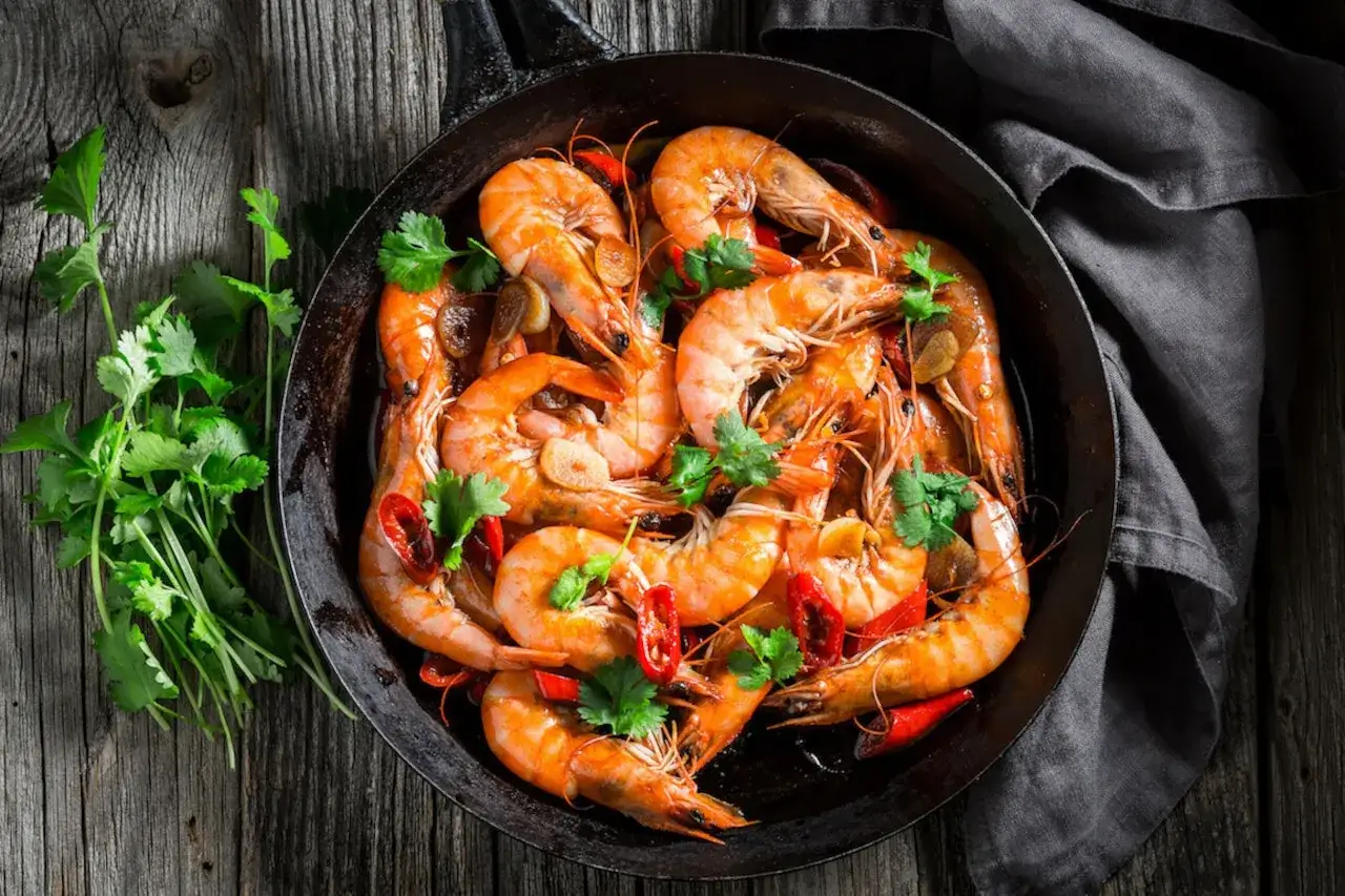 Gotowe do podania krewetki w patelni, z czosnkiem i chili. Dowiedz się, jak oczyścić krewetki, by cieszyć się tym daniem.
