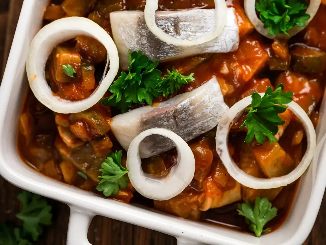 Śledź w sosie pomidorowym z cebulą i natką pietruszki. Czy śledź jest zdrowy? Tak, to bogactwo kwasów omega-3.