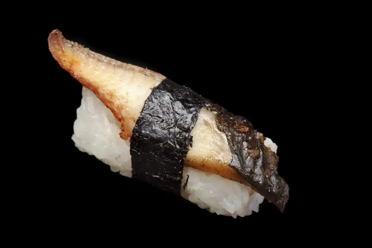 Pyszne sushi z węgorzem, z ryżem i nori, na czarnym tle.