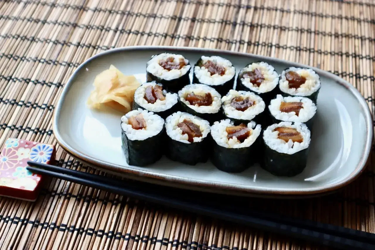 Pyszne sushi z tykwą, podane na talerzu z imbirem, na bambusowej macie.