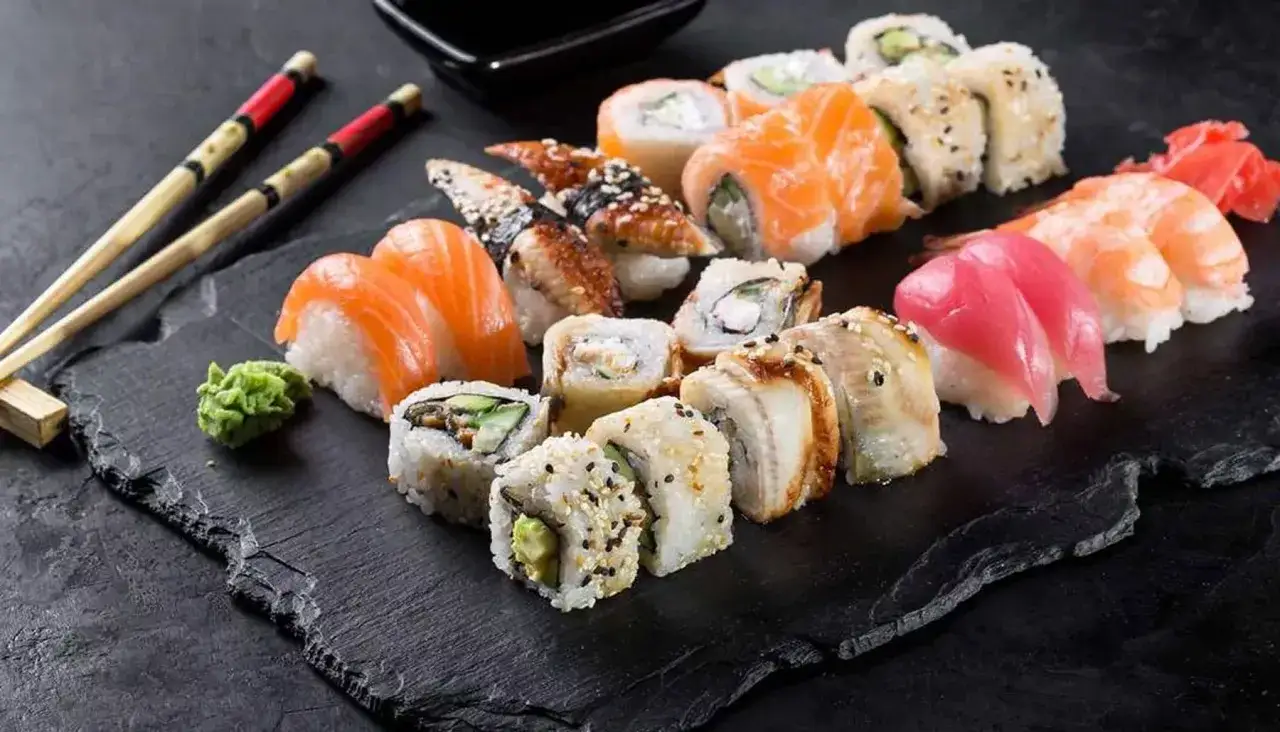 Różnorodne sushi, w tym nigiri z łososiem i krewetkami, oraz maki z węgorzem i awokado. To danie, z jakiego kraju pochodzi sushi, jest symbolem japońskiej kuchni.