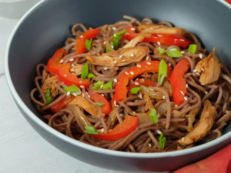 Makaron soba przepis: danie z makaronem gryczanym, kurczakiem, papryką i szczypiorkiem, posypane sezamem.