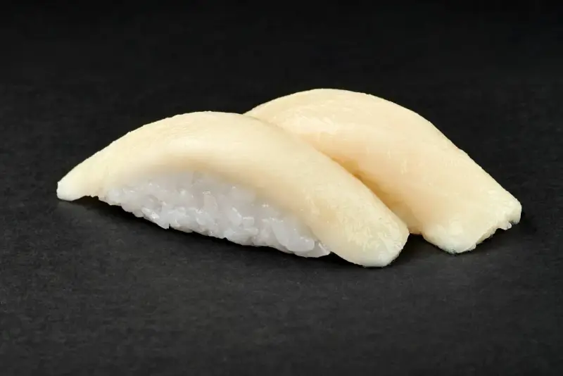Dwa kawałki sushi z rybą maślaną na czarnym tle. Delikatna ryba idealnie komponuje się z ryżem.