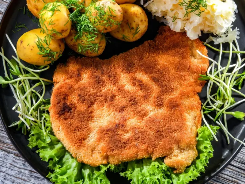 Chrupiący schabowy w panko, podany z młodymi ziemniaczkami, surówką i świeżą sałatą. Prawdziwa uczta dla podniebienia!